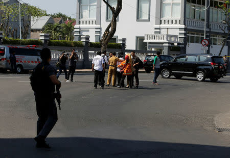 Anti-terror policemen stand guard as officials evacuate Surabaya Mayor Tri Rismaharini (white shirt in center) following a bomb blast at police office in Surabaya, Indonesia May 14, 2018. REUTERS/Beawiharta