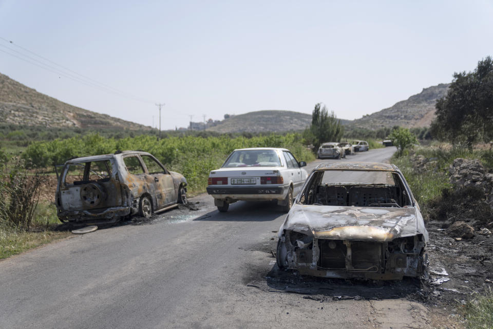 Torched vehicles are seen along the road in the West Bank village of al-Mughayyir, Saturday, April 13, 2024. Dozens of Israeli settlers stormed into a Palestinian village in the Israeli-occupied West Bank on Friday, shooting and setting houses and cars on fire. The rampage killed a Palestinian man and wounded 25 others, Palestinian health officials said. An Israeli rights group said the settlers were searching for a missing 14-year-old boy from their settlement. (AP Photo/Nasser Nasser)