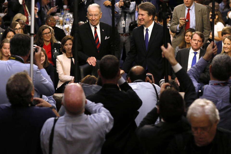 FILE - In this Sept. 4, 2018, file photo Supreme Court nominee Judge Brett Kavanaugh is surrounded by photographers as he stands with Senate Judiciary Committee Chairman Chuck Grassley R-Iowa, during his confirmation hearing on Capitol Hill in Washington. Senate Republicans are moving ahead with Kavnaugh but it’s not at all clear if confirming the conservative judge will provide the mid-term election boost once envisioned or saddle the GOP with political fallout from Christine Blasey Ford’s allegations of sexual assault for years to come.(Jim Bourg/Pool Photo via AP, File)