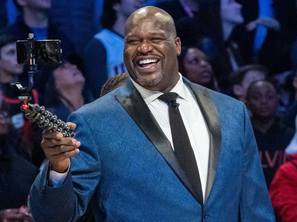 Shaquille O'Neal points and laughs during an NBA event.