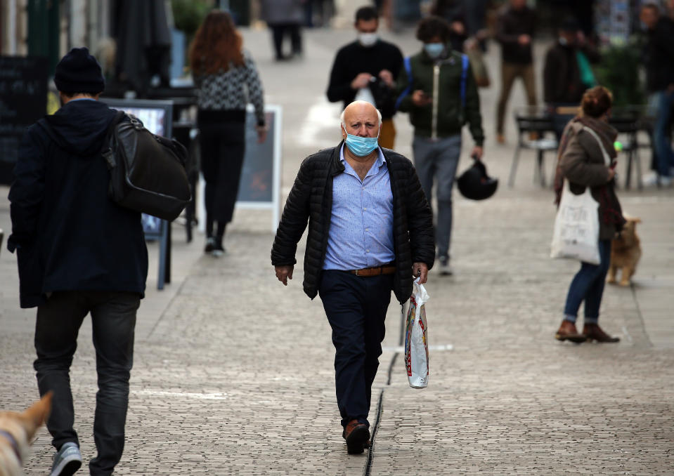 People wearing masks walk the streets of Bayonne, southwestern France, Friday, Oct. 16, 2020. France registered more than 30,000 virus cases Thursday, its highest single-day jump since the pandemic began, and nearly 200 cases per 100,000 people over the past week. (AP Photo/Bob Edme)