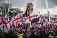 Members of the public look on from a bridge at people holding flags taking part in a march organised by the far-right group Britain First in central London on April 1, 2017 following the March 22 terror attack on the British parliament. Members of the Britain First group and the English Defence League rallied in central London in on seperate marches entitled a "March Against Terrorism" and "We Are Not Afriad" following the terror attack on Westminster Bridge and the British Parliament on March 22 which killed four people. The marches were opposed by the Unite Against Fascism organisation who held a static demonstration against the other groups. / AFP PHOTO / Daniel LEAL-OLIVAS (Photo credit should read DANIEL LEAL-OLIVAS/AFP via Getty Images)