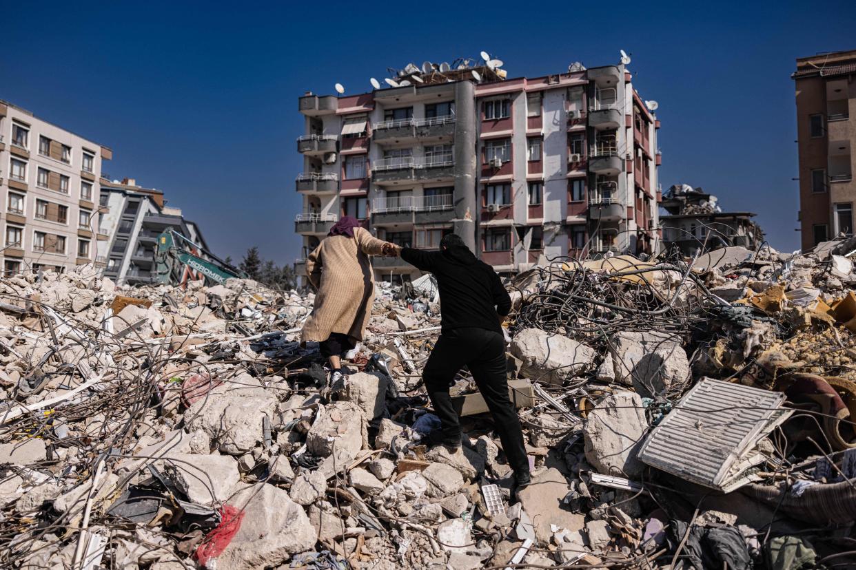 A couple climbs the rubble of collapsed buildings in Antakya, southern Turkey.