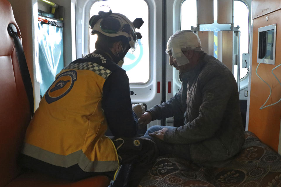 This photo provided by the Syrian Civil Defense White Helmets, which has been authenticated based on its contents and other AP reporting, shows a Syrian White Helmet civil defense worker, left, treats an injured man inside an ambulance, in the town of Afrin, north of Aleppo, Thursday, Jan. 20, 2022. The rocket attack on Afrin, controlled by Turkey-backed opposition fighters, killed several civilians and wounded over a dozen people on Thursday, Syrian rescuers and a war monitor said. Both blamed U.S-backed Syrian Kurdish forces for the attack. (Syrian Civil Defense White Helmets via AP)