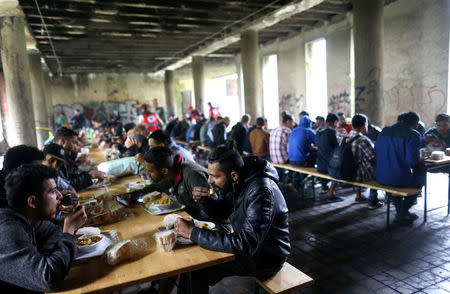 Migrants eat in a dorm destroyed during the Bosnian 1992-1995 war, in Bihac, Bosnia and Herzegovina May 11, 2018. REUTERS/Dado Ruvic