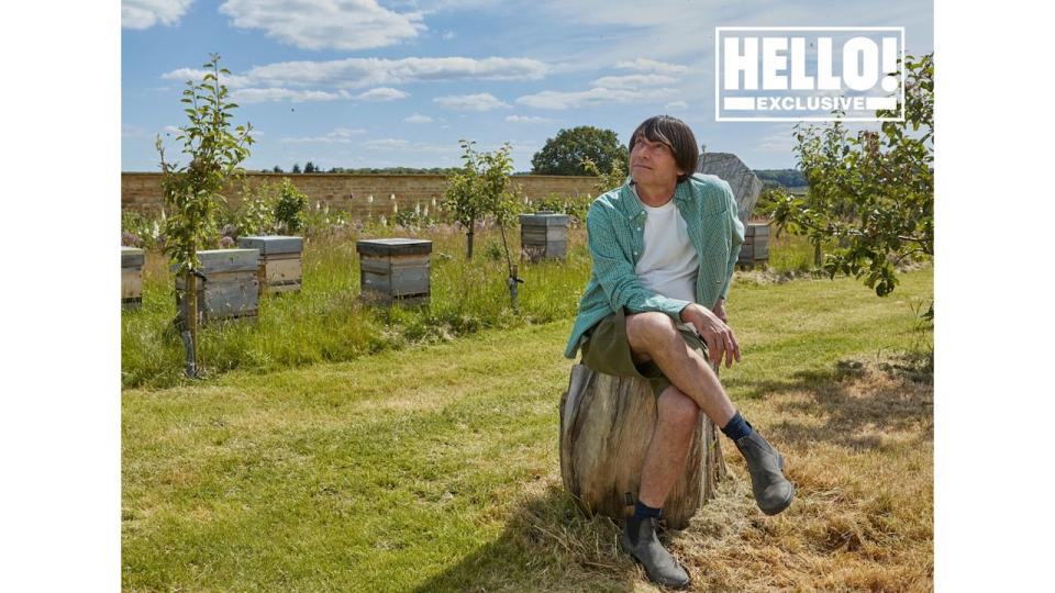 Blur star Alex James posing on tree trunk in field at farmhouse in Kingham, Oxfordshire 