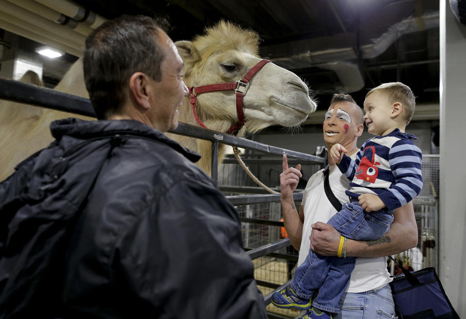 <p>Ringling Bros. boss clown Sandor Eke, center, holds his 2-year-old son Michael up to pet a camel before performing in a show, Friday, May 5, 2017, in Providence, R.I. “When you’re a circus kid you have your own zoo,” said Eke. (Photo: Julie Jacobson/AP) </p>