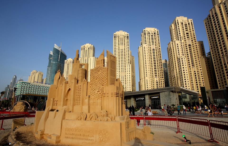 In this Monday, April 21, 2014 photo, people walk past a sand statue depicting famous landmarks of the city at the beach in Dubai, United Arab Emirates. The ribbon of beach nestled along the towering skyscrapers rising from Dubai’s man-made marina district is a rare spot in the Middle East, bringing together the conservatively dressed and the bikini-clad in a multiethnic mix of those with means and those still striving for a more comfortable life. (AP Photo/Kamran Jebreili)