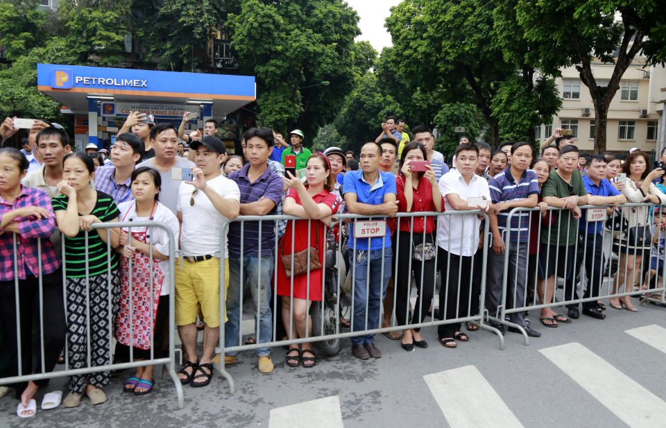 Hanoi residents line a street in Hanoi, Vietnam Thursday, Sept. 27, 2018 to pay last respect to late President Tran Dai Quang who died last week of viral illness. Some were using smart phones to catch images of his flag-draped coffin on truck-drawn artillery carriage. (AP Photo/Tran Van Minh)