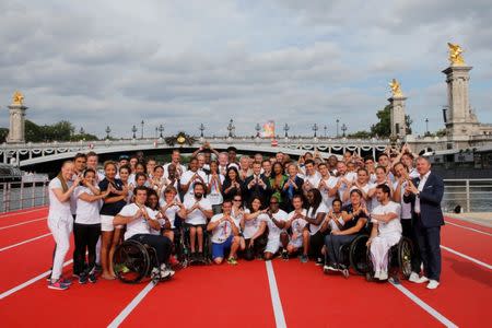 French President Emmanuel Macron (C) stands with city mayor Anne Hidalgo (C Left) and Sports Minister Laura Flessel (C Right) as they pose with athletes for a family photo on an athletics track which floats on the Seine River in Paris, France, June 24, 2017. REUTERS/Jean-Paul Pelissier