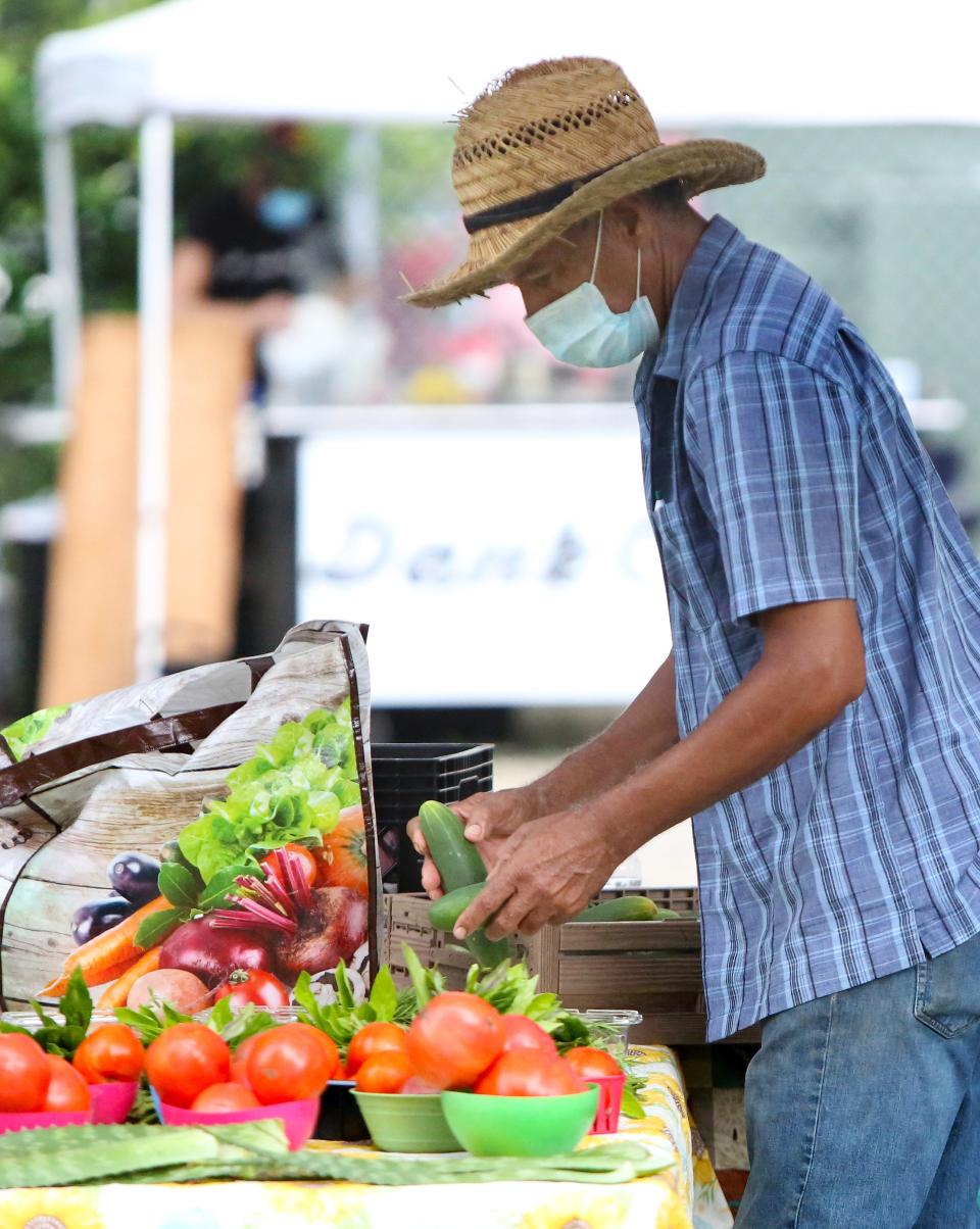 Ramon Angeles organizes some of the vegetable items from his Angeles' Farm at his booth during the Grove Street Farmers Market in Gainesville in 2020.