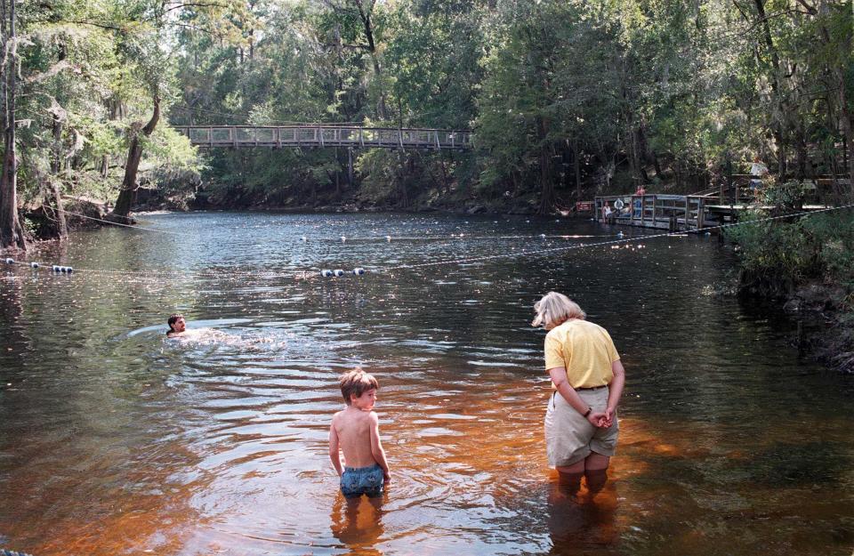 In this 1997 photo, overnight campers Susan Sulouff and her son, Taylor, 6, wade into the Santa Fe, River at O'Leno State Park after their picnic lunch and before going home to Orlando. Weekend cyclist Stephen Perz of Gainesville swims in the background.