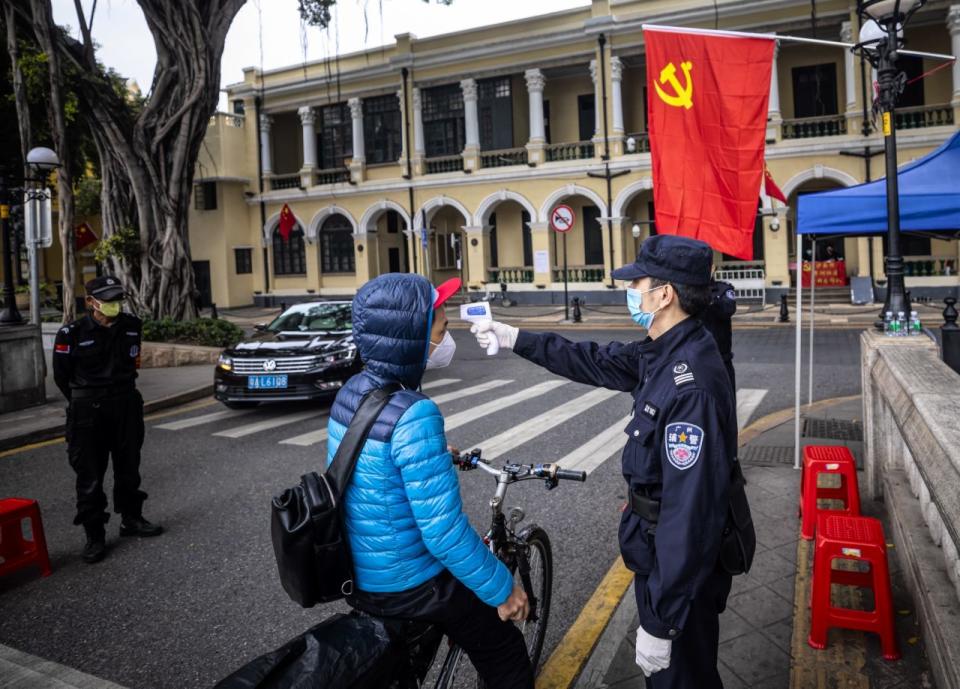 Sicherheitskräfte überprüfen die Körpertemperatur von Menschen an einer Straßensperre in Guangzhou, in der Provinz Guangdong, China. Quelle: AAP