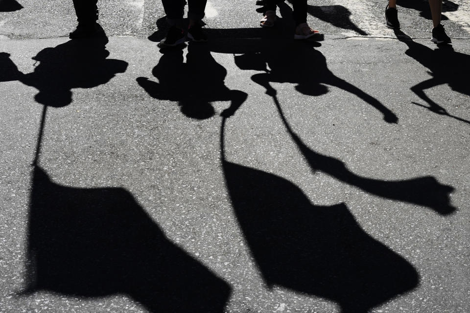 Union workers' shadows are cast on the street as they march with flags on International Workers' Day in Asuncion, Paraguay, May 1, 2024. (AP Photo/Jorge Saenz)