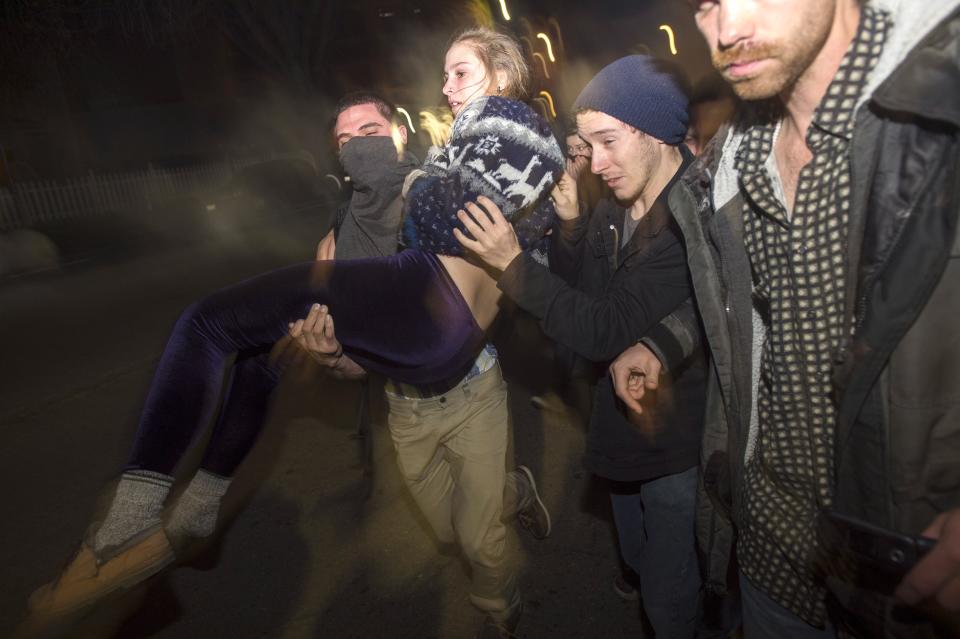 Protesters carry a fellow demonstrator as police officers deploy teargas during a protest against police violence in the U.S., in Berkeley