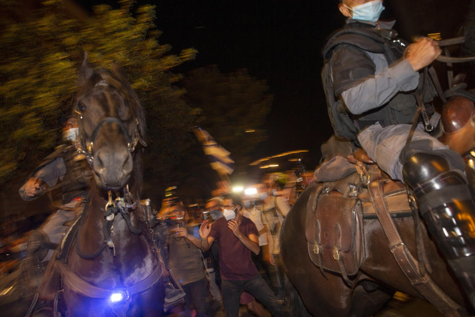 Israeli mounted police officers clash with demonstrators during a protest against Israel's Prime Minister Benjamin Netanyahu outside his residence in Jerusalem, early Sunday, July 26, 2020. Protesters demanded that the embattled Israeli leader resign as he faces a trial on corruption charges and grapples with a deepening coronavirus crisis. (AP Photo/Ariel Schalit)