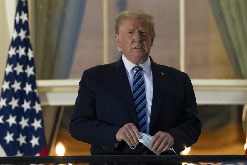 FILE - In this Monday, Oct. 5, 2020 file photo, President Donald Trump removes his mask as he stands on the Blue Room Balcony upon returning to the White House in Washington, after leaving Walter Reed National Military Medical Center, in Bethesda, Md. Trump announced he tested positive for COVID-19 on Oct. 2. (AP Photo/Alex Brandon)