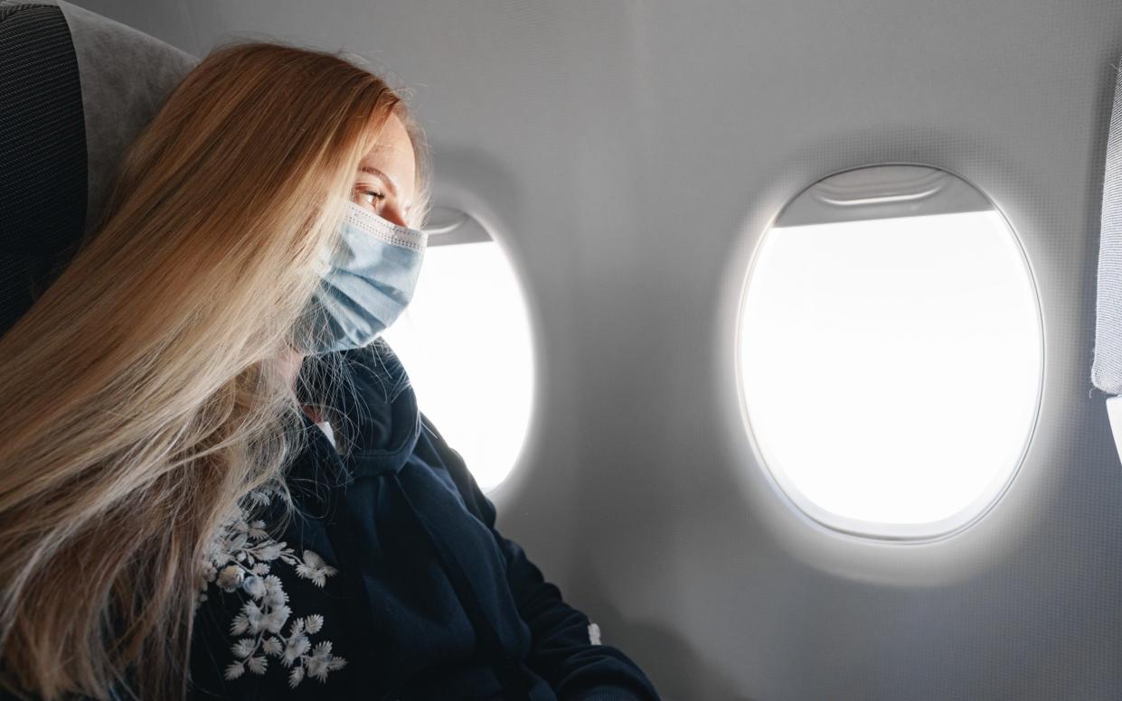 woman wearing mask plane - Getty