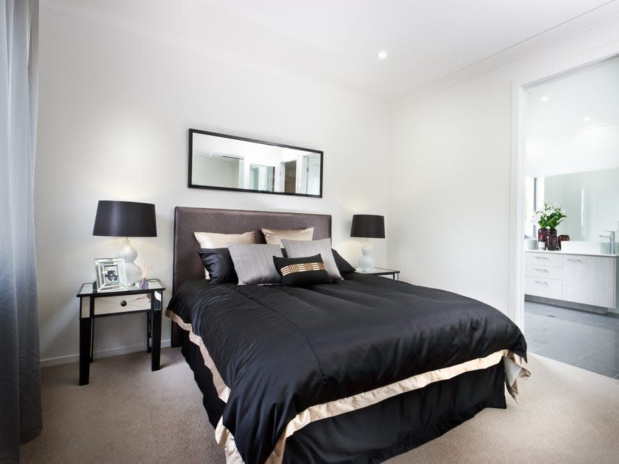 white bedroom with black comforter and dark headboard with side table and black lamp