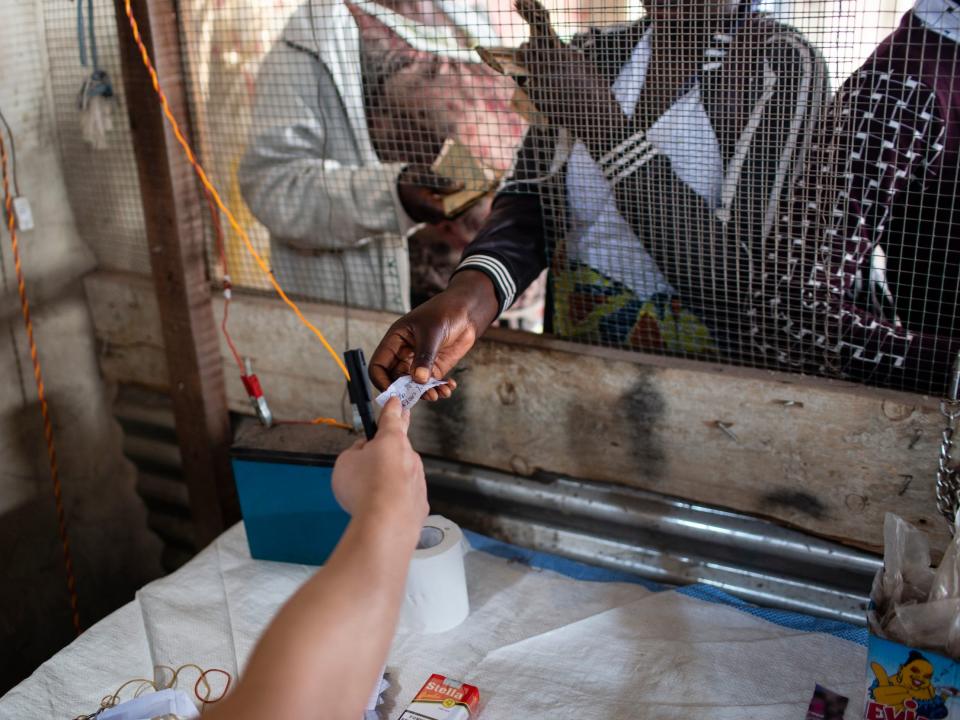 A man from China gives a cobalt mining worker a pay slip at the Musompo market