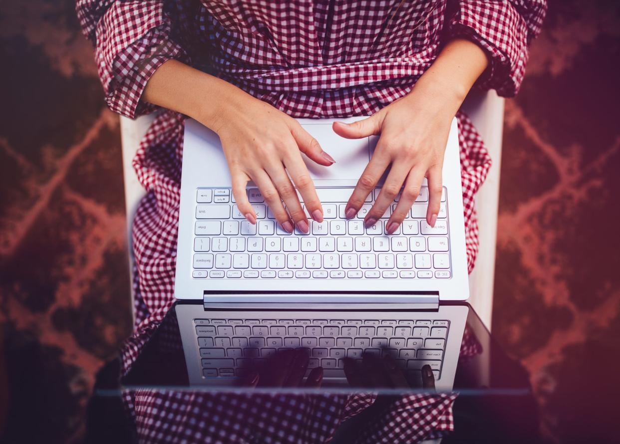 Woman sitting in chair writing emails on laptop