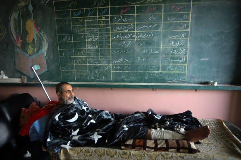 Seorang pemuda Palestina yang terluka dari kamp Jabalia terbaring di tempat tidur setelah dipindahkan dari rumah sakit Indonesia di utara ke sebuah sekolah di Khan Yunis, pada hari Rabu.  Qatar dan Mesir memainkan peran penting dalam memfasilitasi pertukaran sandera.  Foto oleh Ismail Muhammad/UPI