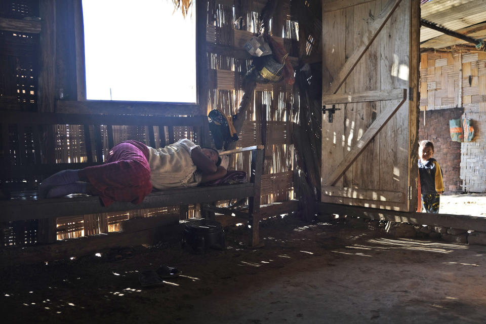 Awan, whose 23-year old twin sons were killed by Indian army soldiers, lies grieving on a bench inside the traditional bamboo and palm leaf roofing kitchen built by her sons in Oting village, in the northeastern Indian state of Nagaland, Wednesday, Dec. 15, 2021. The twins had gone out as part of a rescue team to find eight missing villagers, six of whom had already been killed by the soldiers. Oting village is in mourning after more than a dozen people were killed by soldiers. (AP Photo/Yirmiyan Arthur)