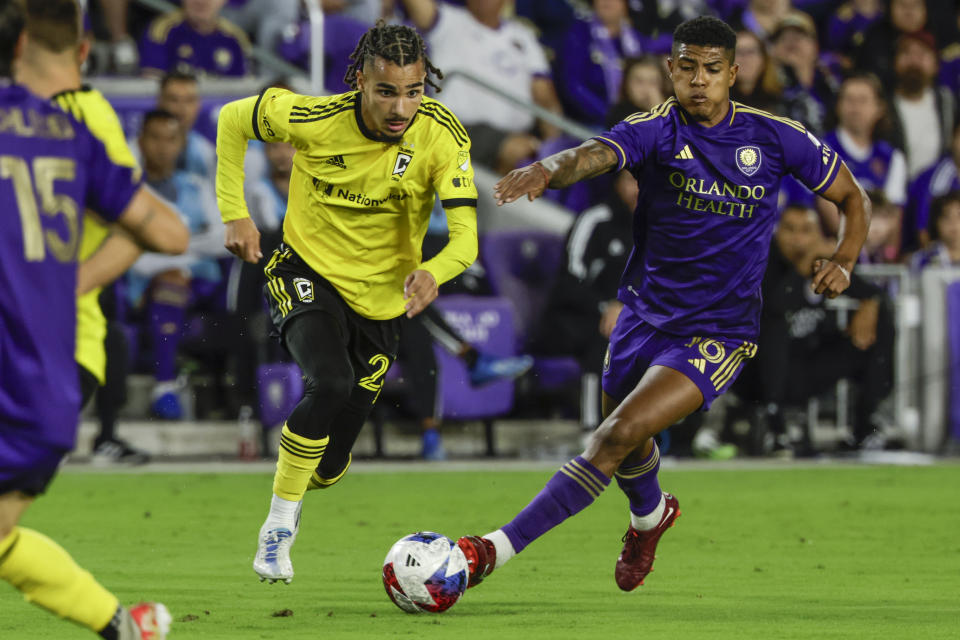 Columbus Crew defender Mohamed Farsi, right, is defended by Orlando City midfielder Wilder Cartagena, left, during the first half of an MLS soccer playoff match, Saturday, Nov. 25, 2023, in Orlando, Fla. (AP Photo/Kevin Kolczynski)