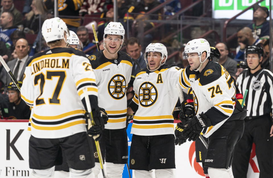 Boston Bruins' Brad Marchand, second from right, celebrates with teammates, from left, Hampus Lindholm, Brandon Carlo and Jake DeBrusk after scoring a goal against the Vancouver Canucks during the first period of an NHL hockey game, Saturday, Feb. 25, 2023 in Vancouver, British Columbia. (Rich Lam/The Canadian Press via AP)