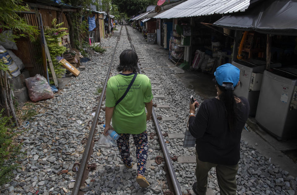 Darunee Khedkhow, right and Jariya Saekean, teachers of Makkasan preschool, walk along a railway line to deliver meals in Bangkok, Thailand, Wednesday, June 24, 2020. During the third month that schools remained closed due to the coronavirus outbreak, teachers have cooked meals, assembled food parcels and distributed them to families in this community sandwiched between an old railway line and a khlong, one of Bangkok’s urban canals. (AP Photo/Gemunu Amarasinghe)