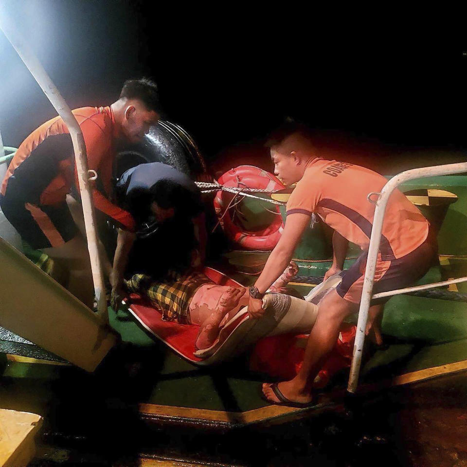 In this photo provided by the Philippine Coast Guard, rescuers from the coast guard (orange shirts) carry a survivor of a vessel that caught fire at the vicinity waters off Naga City, Cebu, Philippines Wednesday, June 5, 2024. Several crew members of a fishing boat were killed when an explosion and a fire hit their vessel at sea nearly three kilometers (3.7 miles) off a central Philippine province, coast guard officials said Thursday, adding several others were rescued. (Philippine Coast Guard via AP)