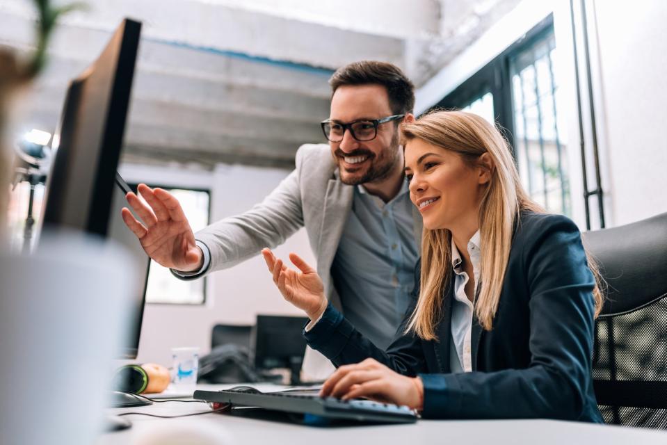 Two investors smile while looking at something on a computer screen.