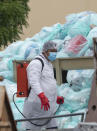 A medical worker using protective equipment disinfects a large pile of hazardous biological waste outside the Hospital del Instituto Mexicano del Seguro Social, which treats patients with COVID-19 in Veracruz, Mexico, Wednesday, Aug. 12, 2020. Improper disposal of medical waste has become an increasing problem in Mexico amid the pandemic. (AP Photo/Felix Marquez)