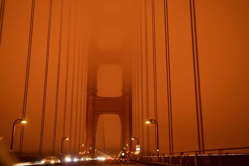 Cars drive along the San Francisco Bay Bridge under an orange smoke filled sky at midday in San Francisco, California on September 9, 2020. - More than 300,000 acres are burning across the northwestern state including 35 major wildfires, with at least five towns "substantially destroyed" and mass evacuations taking place. (Photo by Harold POSTIC / AFP) (Photo by HAROLD POSTIC/AFP via Getty Images)