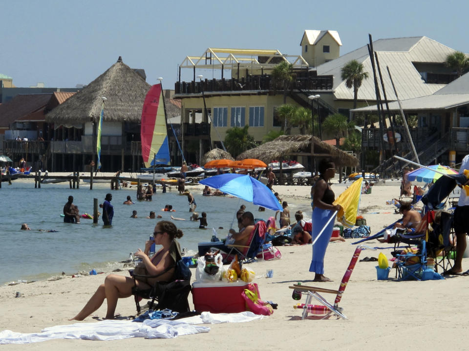 FILE - This Aug. 28, 2011 file photo shows tourists as they sit on the beach at Pensacola Beach, Fla. The white sand beaches and turquoise waters of Florida's Panhandle draw millions of visitors each year, from college spring breakers to families on summer vacation. (AP Photo/Melissa Nelson, file)