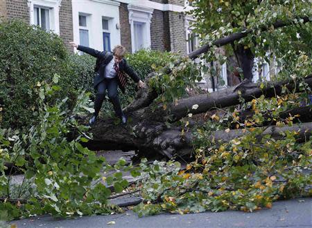 Theo Harcourt, a 13-year-old student, jumps over a fallen tree as he makes his way to school in Islington, north London October 28, 2013, after strong storm winds and rain battered southern parts of England and Wales early on Monday, forcing flight cancellations, disrupting trains and closing roads and major bridges before the start of rush-hour. REUTERS/Olivia Harris