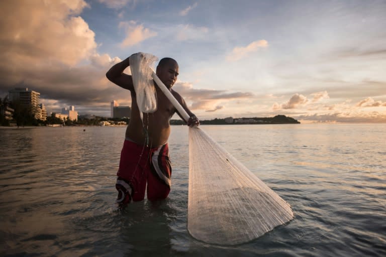 A fisherman works off a beach at Tumon Bay in Guam