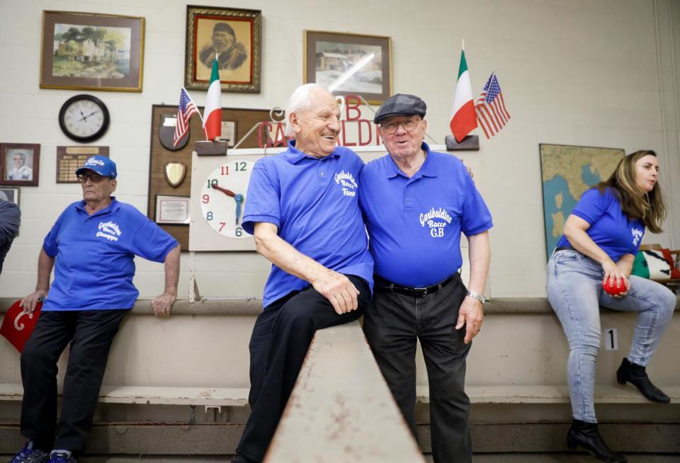 Two men in polo shirts embrace while playing bocce ball at the Garibaldina Society.