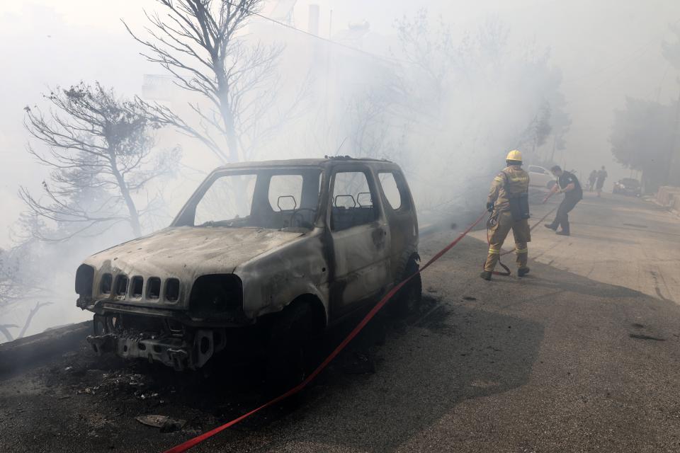 A firefighter and policeman operate during a wildfire in Voula suburb, in southern Athens, Greece, Saturday, June 4, 2022. A combination of hot, dry weather and strong winds makes Greece vulnerable to wildfire outbreaks every summer. (AP Photo/Yorgos Karahalis)