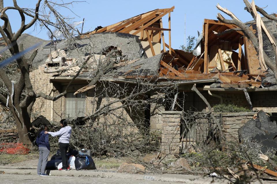 Women stand outside a house damaged by a tornado in the Preston Hollow section of Dallas: AP