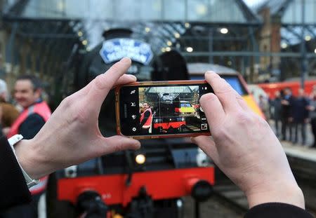 A man takes a photo as the Flying Scotsman steam engine prepares to leave Kings Cross station in London, February 25, 2016. REUTERS/Paul Hackett