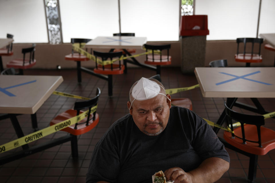 A dine-in customer with a face mask on his head is surrounded by tables marked with X's for social distancing at a restaurant in Los Angeles, Wednesday, July 1, 2020. California Gov. Gavin Newsom has ordered a three-week closure of bars and indoor operations of restaurants and certain other businesses in Los Angeles and 18 other counties as the state deals with increasing cases of COVID-19. (AP Photo/Jae C. Hong)