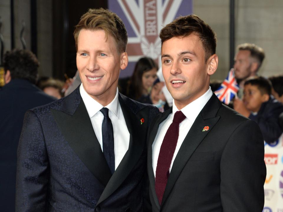 Dustin Lance Black and Tom Daley in suits on a red carpet