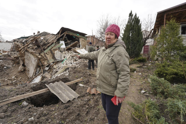 Tetiana Iegorova, 55, who is internally displaced points to her neighbour's house which was destroyed by a Russian rocket in Kharkiv, Ukraine, Friday, March 31, 2023. (AP Photo/Andrii Marienko)