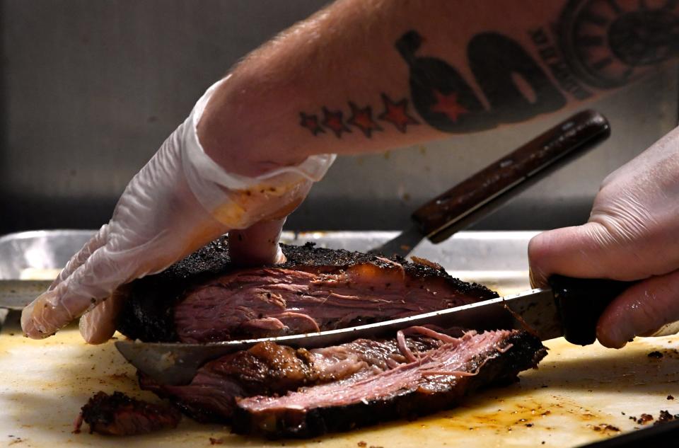 Texas Cowboy BBQ owner George Mulaj slices brisket for a lunch plate Friday.