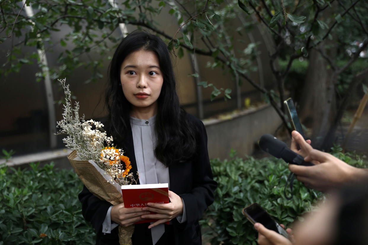 Zhou Xiaoxuan steht mit Blumen und einem Buch vor dem Gericht, in dem das Verfahren wegen sexueller Belästigung stattfand. 