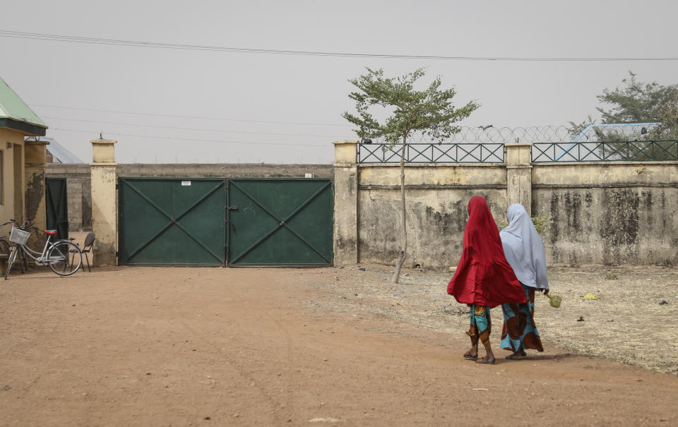 Girls walk next to the Government Girls Junior Secondary School from where more than 300 girls were abducted on Friday by gunmen, in Jangebe town, Zamfara state, northern Nigeria Saturday, Feb. 27, 2021. Nigerian police and the military have begun joint operations to rescue the more than 300 girls who were kidnapped from the boarding school, according to a police spokesman. (AP Photo/Ibrahim Mansur)