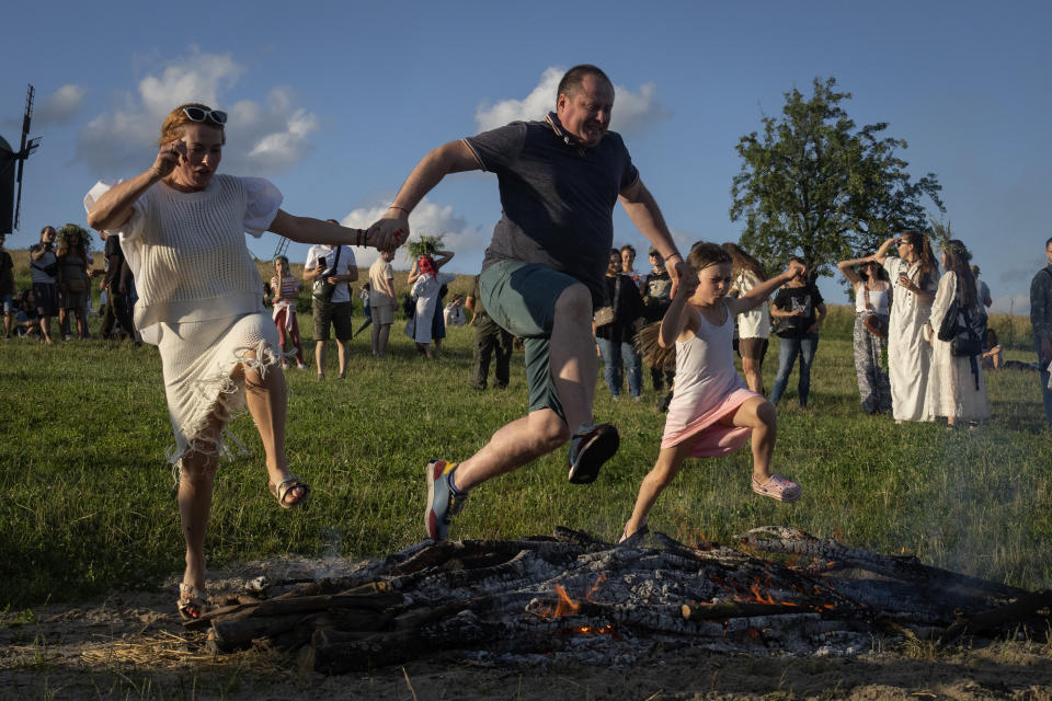 A family jumps over the fire at a traditional Midsummer Night celebration near capital Kyiv, Ukraine, Sunday, June 23, 2024. The age-old pagan festival is still celebrated in Ukraine amid the third year of Russia-Ukraine war. Many people believe that jumping over the fire will cleanse them of evil spirits.(AP Photo/Efrem Lukatsky)