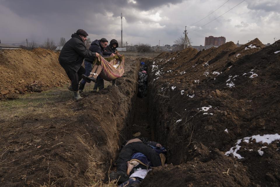 Bodies are placed into a mass grave on the outskirts of Mariupol, Ukraine, March 9, 2022. The image was part of a series of images by Associated Press photographers that was awarded the 2023 Pulitzer Prize for Breaking News Photography. (AP Photo/Evgeniy Maloletka)