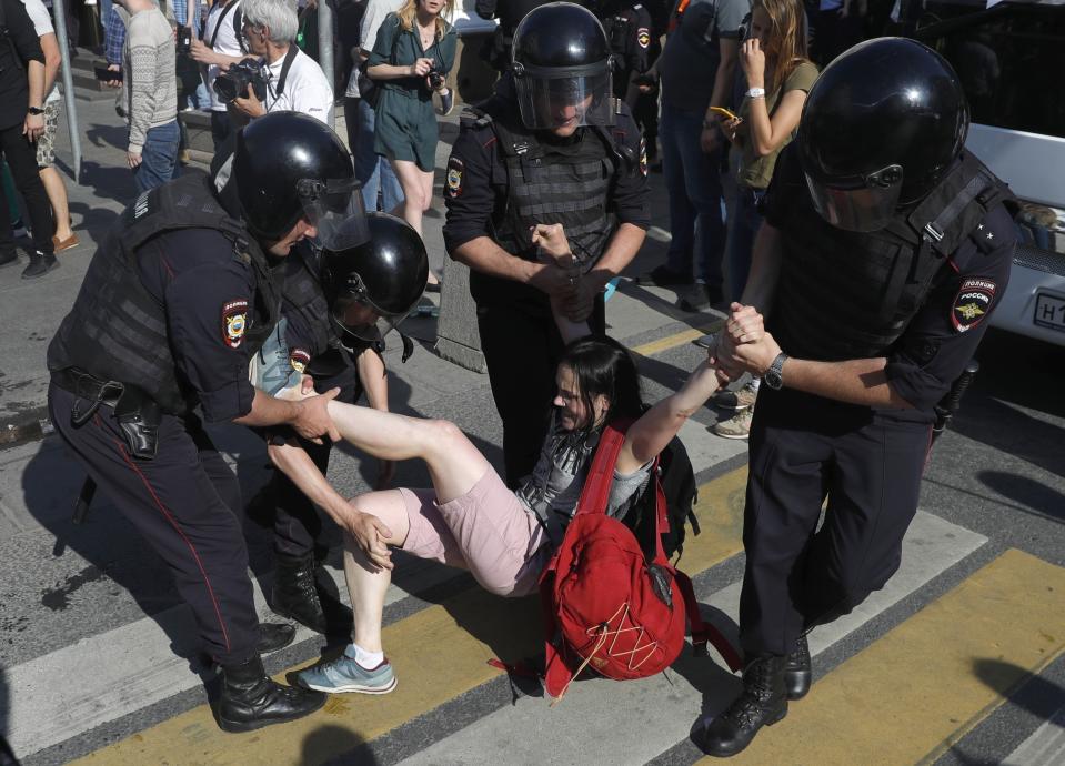 Police officers detain a woman during an unsanctioned rally in the center of Moscow, Russia, Saturday, July 27, 2019. Russian police clashed with demonstrators and have arrested some hundreds in central Moscow during a protest demanding that opposition candidates be allowed to run for the Moscow city council. (AP Photo/ Pavel Golovkin)